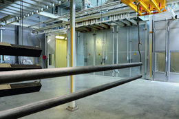 Das Teilespektrum reicht vom Kleinteil bis hin zu 1600 kg schweren Maschinenkörpern. Im Hintergrund (v.l.n.r.): Pulverkabine, Einbrennofen, Haftwassertrockner und Reinigungs- /Vorbehandlungskabine.