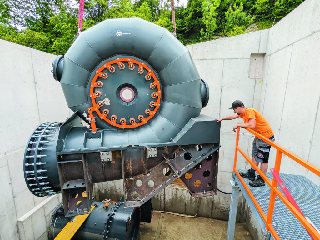 Ein Mann steht neben einer riesigen Kraftwerksturbine.