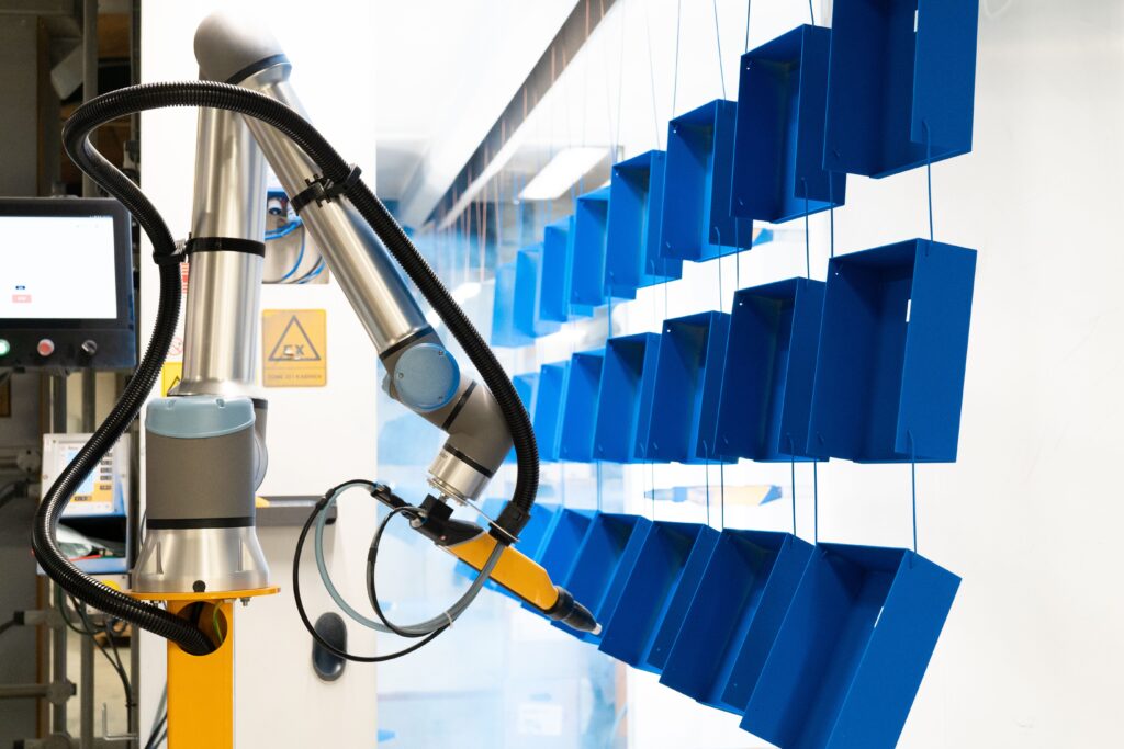 Ein Roboter beschichtet Bauteile mit Pulverlack.