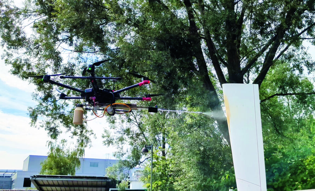 Eine fliegende Drohne lackiert ein Werkstück.