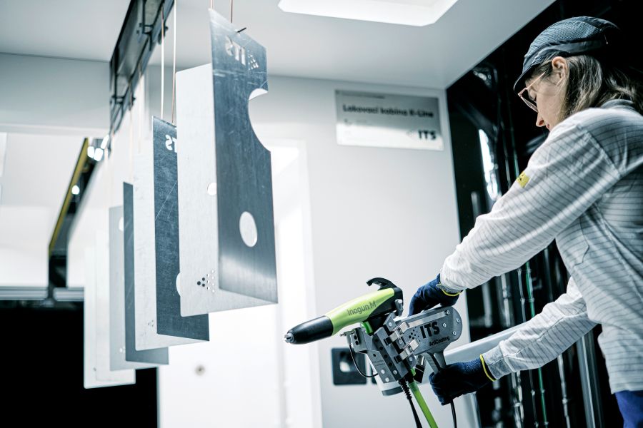 Eine Lackiererin programmiert einen Lackierroboter