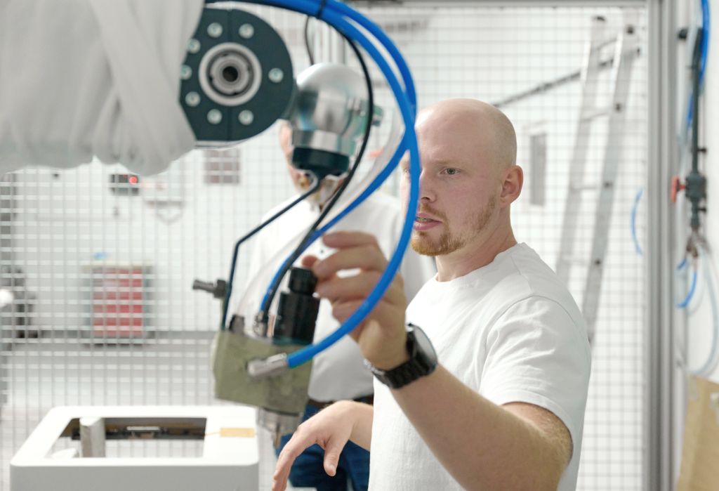 Mann an einem Lackierroboter